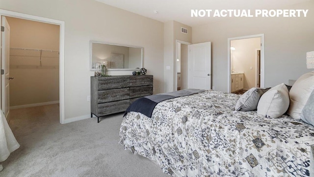 carpeted bedroom with a walk in closet, a closet, baseboards, and visible vents
