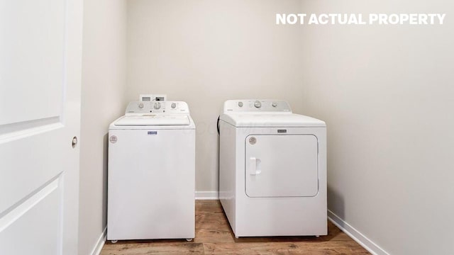 washroom featuring washer and dryer, light wood-type flooring, laundry area, and baseboards