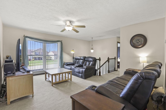 carpeted living area featuring ceiling fan and a textured ceiling