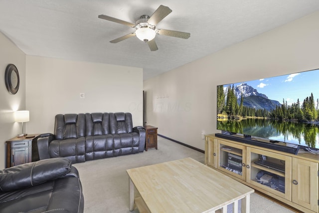 living room with light carpet, a textured ceiling, baseboards, and ceiling fan