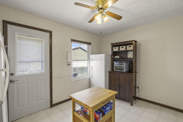 foyer entrance with a textured ceiling, baseboards, a ceiling fan, and light floors