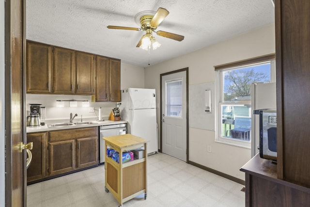 kitchen with dishwasher, a sink, ceiling fan, freestanding refrigerator, and light floors