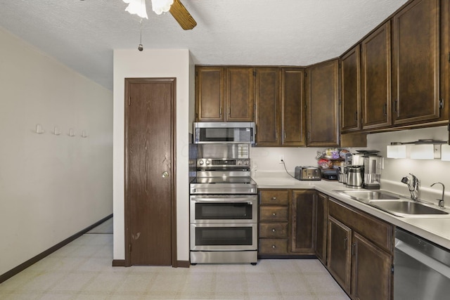 kitchen featuring dark brown cabinetry, a ceiling fan, appliances with stainless steel finishes, light countertops, and a sink