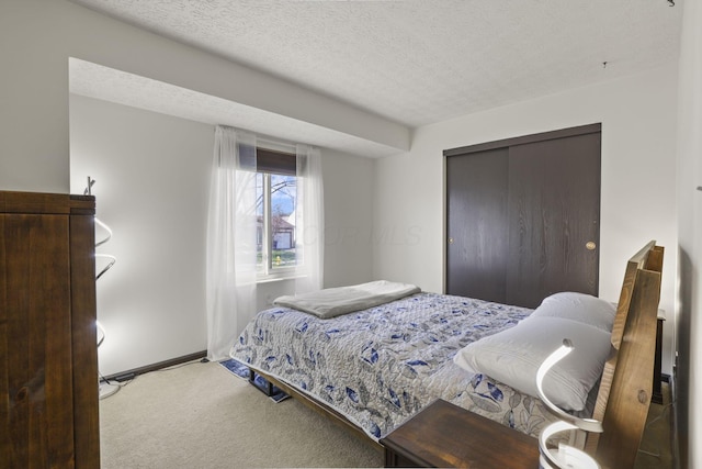 carpeted bedroom featuring baseboards, a closet, and a textured ceiling