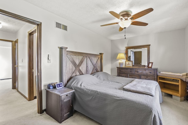 bedroom with visible vents, baseboards, light colored carpet, and a textured ceiling