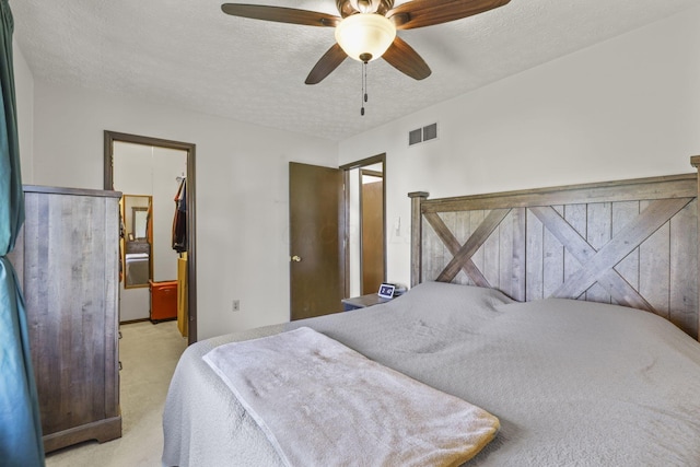bedroom featuring visible vents, a ceiling fan, light colored carpet, and a textured ceiling