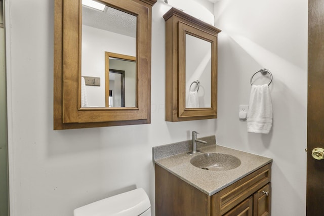 half bathroom with toilet, a textured ceiling, and vanity