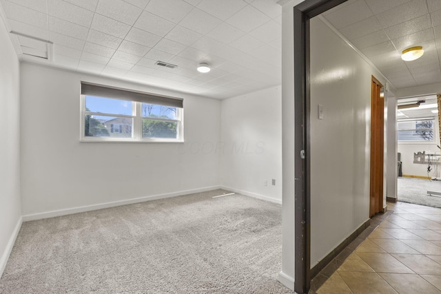 unfurnished room featuring visible vents, baseboards, carpet, a drop ceiling, and tile patterned flooring