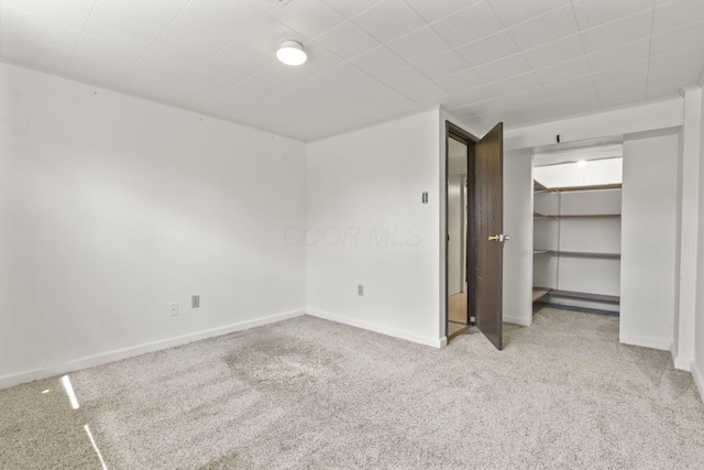 unfurnished bedroom featuring a closet, baseboards, a walk in closet, and carpet floors