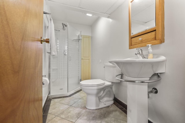 bathroom featuring a paneled ceiling, baseboards, tile patterned floors, toilet, and a shower stall