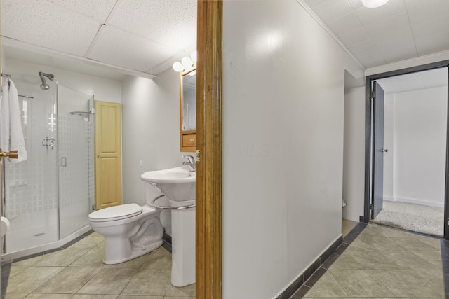 bathroom with toilet, a stall shower, baseboards, and tile patterned flooring