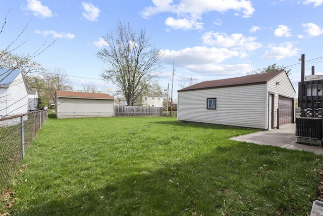 view of yard featuring central AC unit, fence, an outbuilding, and a detached garage