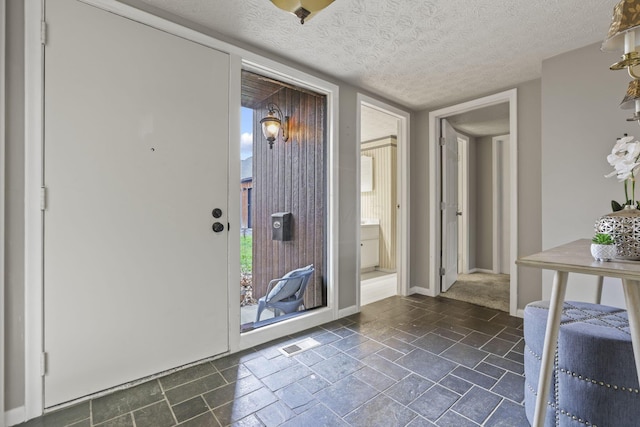 foyer with visible vents, a textured ceiling, and baseboards