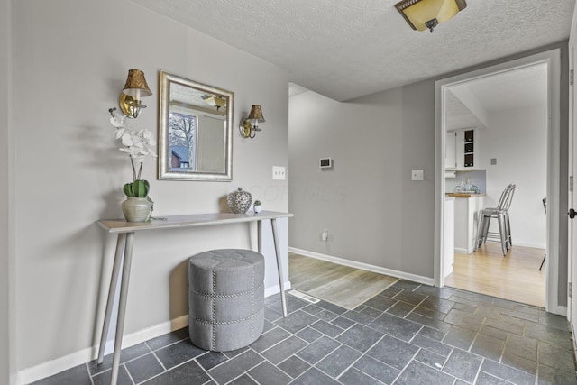 entryway with stone tile flooring, baseboards, and a textured ceiling