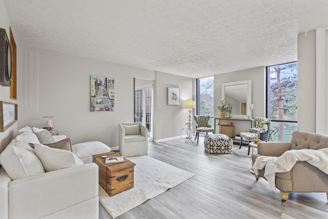 living room with a textured ceiling, baseboards, and wood finished floors