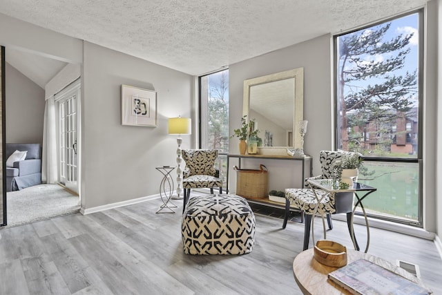 living area featuring visible vents, a textured ceiling, baseboards, and wood finished floors