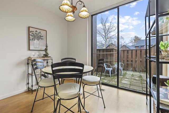 dining space featuring a chandelier, wood finished floors, and baseboards