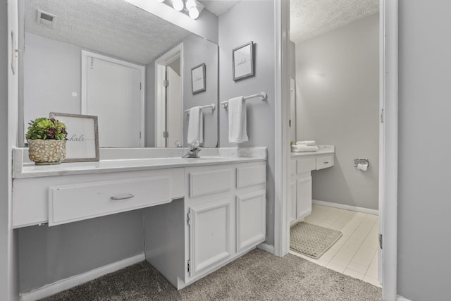 bathroom with visible vents, vanity, tile patterned flooring, and a textured ceiling