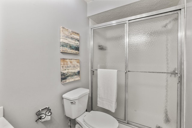 bathroom featuring toilet and a shower stall