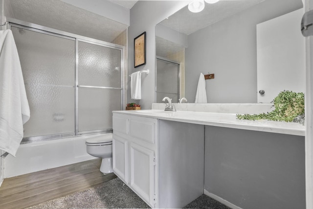 full bathroom featuring toilet, shower / bath combination with glass door, wood finished floors, and vanity