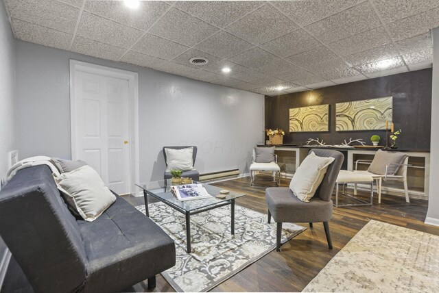 living room with a paneled ceiling, visible vents, recessed lighting, wood finished floors, and a baseboard heating unit