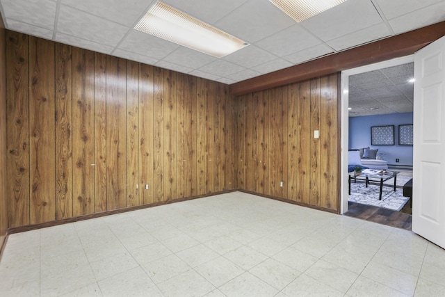 empty room with wooden walls, tile patterned floors, and a paneled ceiling