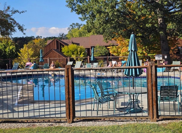 pool with a patio area and fence