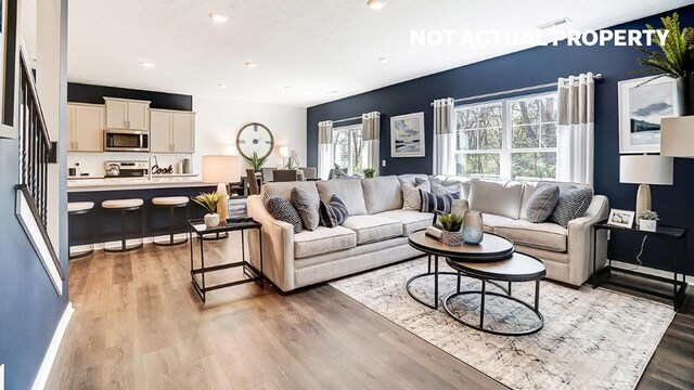living room featuring light wood-style floors, baseboards, visible vents, and recessed lighting