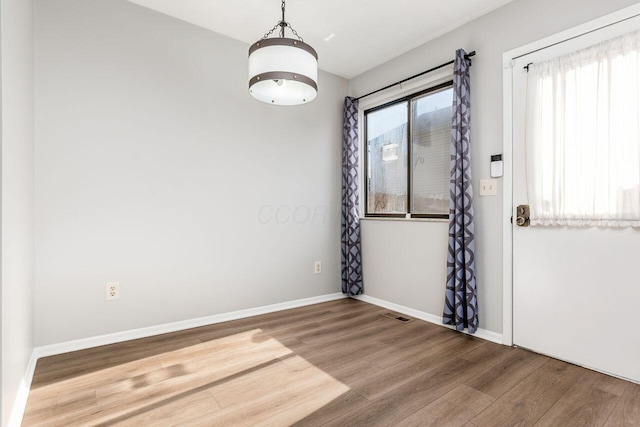 unfurnished room featuring visible vents, baseboards, and wood finished floors