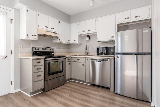 kitchen featuring stainless steel appliances, light wood-style floors, white cabinetry, light countertops, and under cabinet range hood