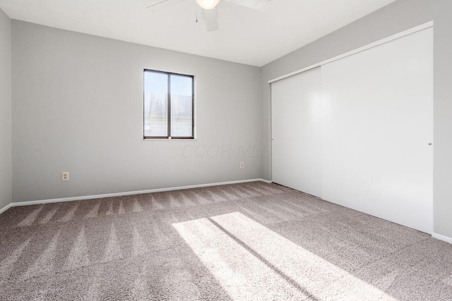 carpeted empty room featuring ceiling fan and baseboards