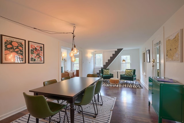 dining area with dark wood-style flooring, baseboards, and stairs