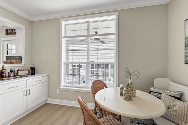 dining room featuring light wood-style flooring, baseboards, and ornamental molding