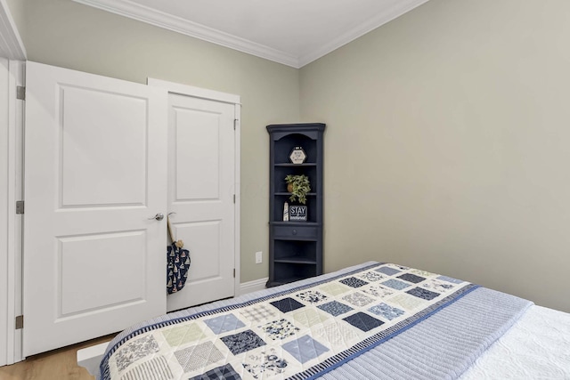 bedroom featuring light wood finished floors, baseboards, and crown molding