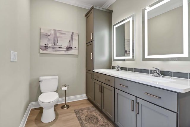 bathroom with baseboards, a sink, toilet, and wood finished floors