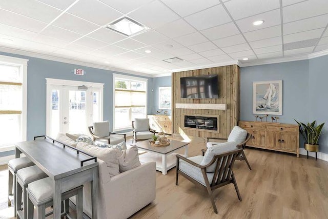 living room featuring a large fireplace, light wood-style flooring, french doors, crown molding, and visible vents