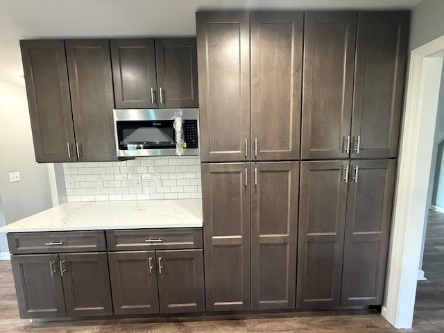 9465 Santa Clara Cir, Plain City, OH 43064 - kitchen with decorative backsplash, baseboards, dark wood-type flooring, stainless steel microwave, and light stone counters