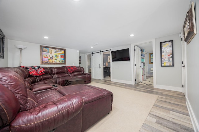 living room with light wood-style floors, baseboards, recessed lighting, and a barn door