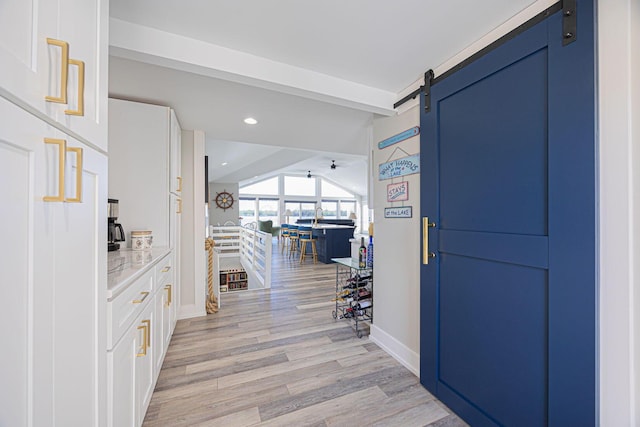 foyer entrance with beamed ceiling, a barn door, baseboards, recessed lighting, and light wood finished floors