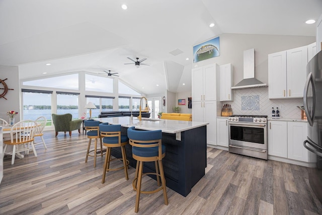 kitchen with gas stove, wall chimney exhaust hood, a sink, and vaulted ceiling