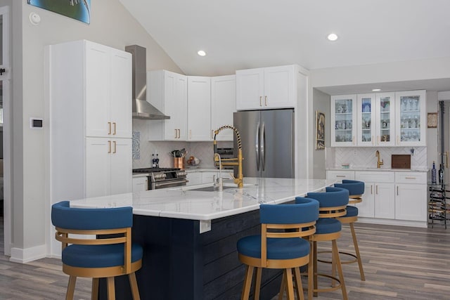 kitchen featuring white cabinets, backsplash, appliances with stainless steel finishes, and wall chimney range hood