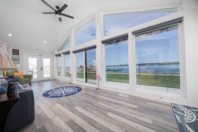 living area with wood finished floors, a water view, ceiling fan, visible vents, and french doors