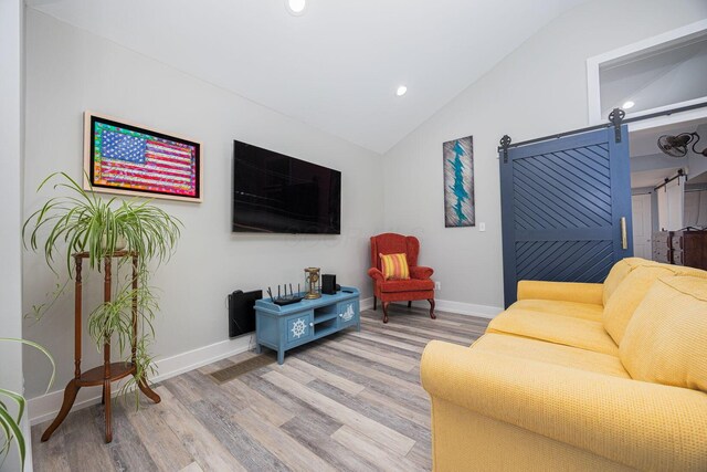 living area featuring light wood finished floors, recessed lighting, a barn door, vaulted ceiling, and baseboards