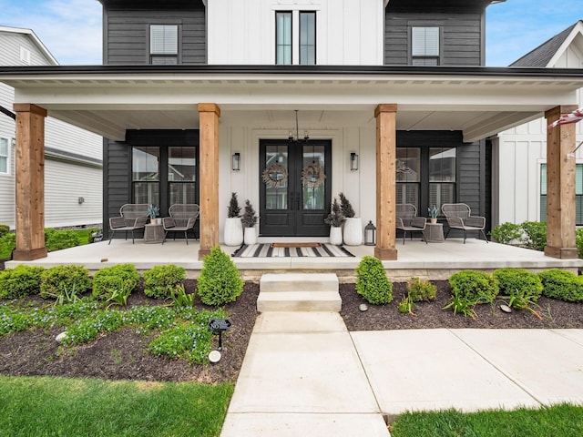 view of exterior entry featuring a porch, board and batten siding, and french doors