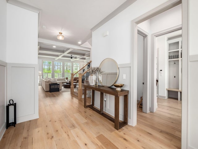 corridor featuring light wood-style floors, beam ceiling, stairway, and coffered ceiling