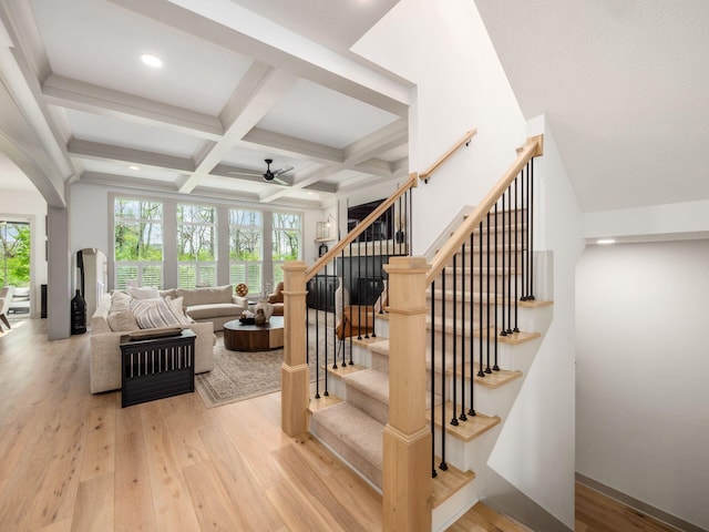 stairway with plenty of natural light, a ceiling fan, hardwood / wood-style floors, and beamed ceiling