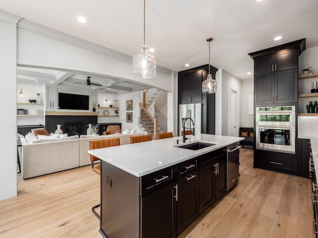 kitchen with light countertops, a glass covered fireplace, a sink, and light wood-style flooring