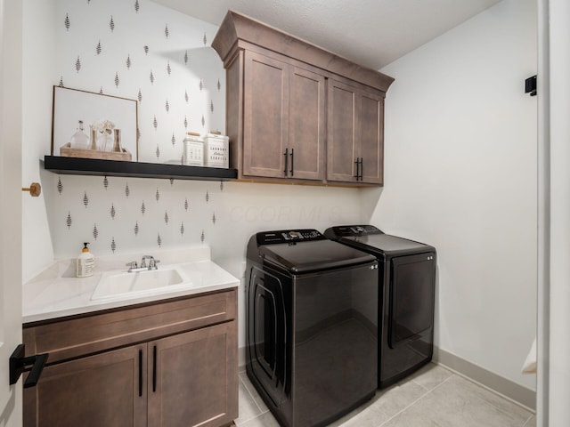 laundry area featuring washing machine and clothes dryer, light tile patterned flooring, a sink, and cabinet space