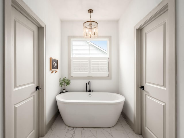 full bathroom featuring baseboards, a chandelier, a soaking tub, and marble finish floor