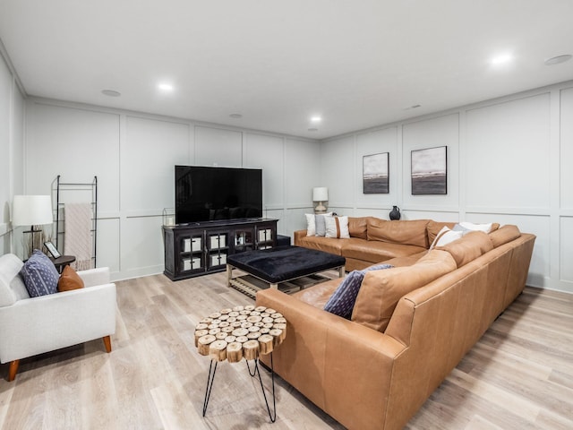 living area with a decorative wall, recessed lighting, and light wood-style flooring